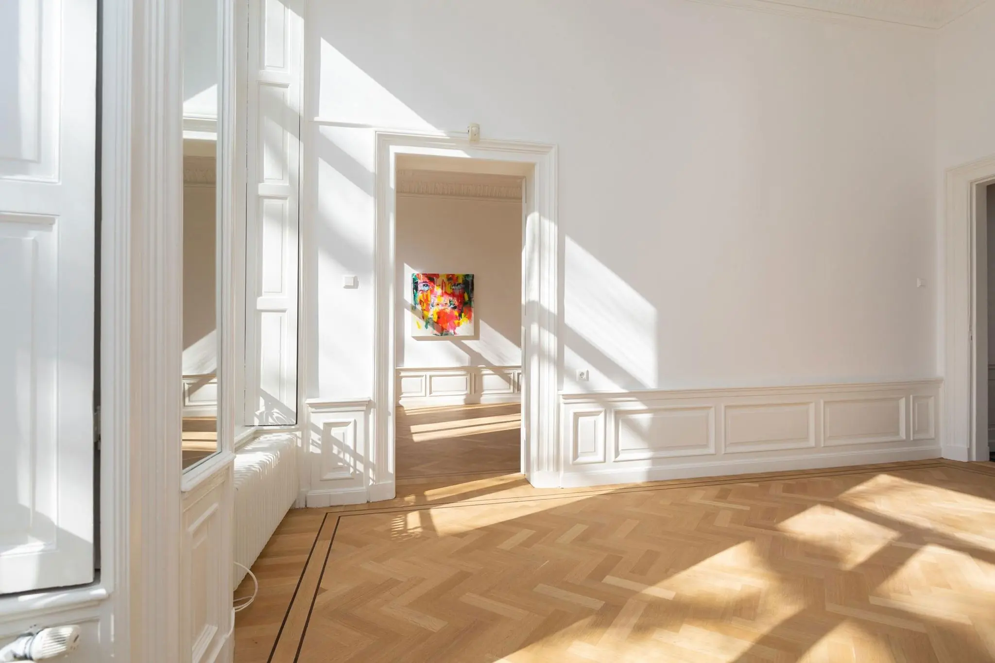 Lichte, klassieke kamer aan het Lange Voorhout met visgraatvloer en kleurrijk schilderij aan de muur.